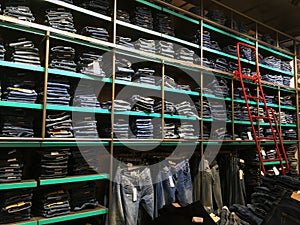 Piles of modern jeans of different sizes. A wide selection of jeans in a clothing store. Shelves with clothes in the department of