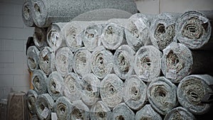 Piles of new rolls of carpet in a store warehouse. Close up