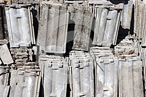 Piles of old gray concrete roof tiles. Building debris. Recycling roof tile waste
