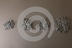 Piles of safety pins on grey textured background, flat lay