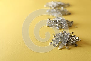 Piles of safety pins on yellow background, space for text
