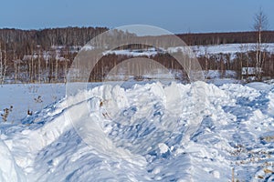 Piles of snow after the work of a tractor to clear rural roads in winter the consequences of heavy snowfall