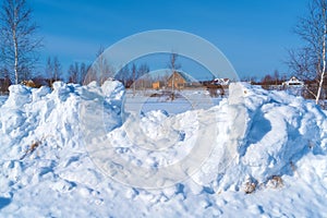 Piles of snow after the work of a tractor to clear rural roads in winter the consequences of heavy snowfall