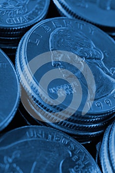 Piles of US American coins of 25 cents quarters close-up. Dark blue vertical background for news about USA money, economy,