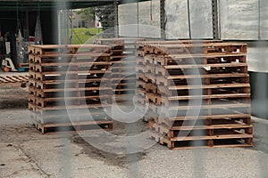 piles of wood palettes skids on pavement in outdoor canopy tent greenhouse