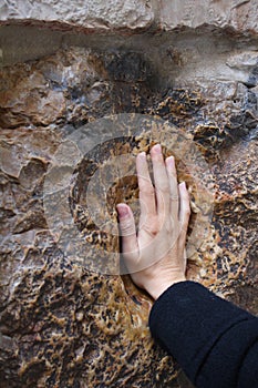 A pilgrim blesses a cross with Jesus hand print, in Via Dolorosa station 5 photo