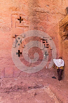 Pilgrim praying at the wall of the Bete Medhane Alem church in Lalibela Ethiopia