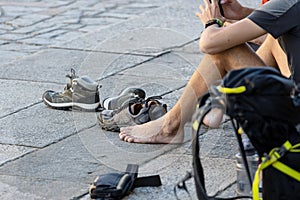 Pilgrim resting sitting barefoot in Obradoiro square after the final route of the Camino de Santiago photo