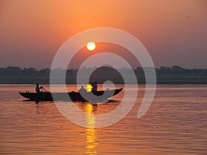 Pilgrims floating by boat of the sacred Ganges river. Sunrise in Varanasi, Uttar Pradesh, India.