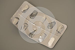 Pill blister pack with missing tablets on gray background