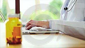 Pill bottle with female doctor using laptop computer