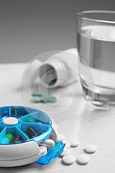 Pill box with medicaments on white wooden table, closeup