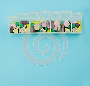 Pill box with pills and vitamins. View from above. Plastic pill box on a blue background