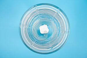 Pill dissolves in a glass of water on a blue background top view