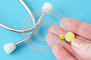 Pill in hand, stethoscope on blue background