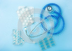 Pill tablet capsule medicine stethoscope through water drops background