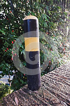 A pillar dividing the road with a black and yellow ravine