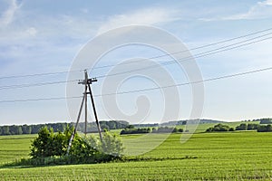 A pillar for electricity on a bright green field against the backdrop of a beautiful sunset sky