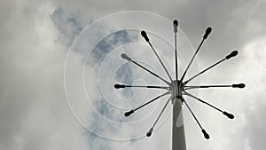 A pillar with a few lanterns against a cloudy sky.