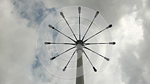 A pillar with a few lanterns against a cloudy sky.