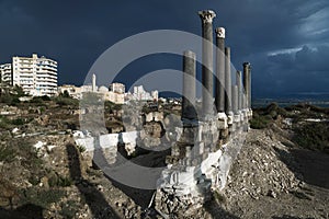 Pillars with cityscape in sunlight during storm in ruins with dramatic cloudscape in Tyre, Sour, Lebanon