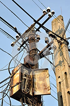 Pillars with old rusty box and crossing cables