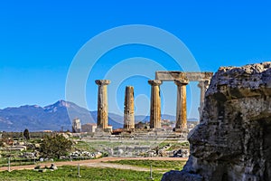 Pillars from Temple of Apollo in Ancient Corinth Greece and background of local picturesque church and mountians on mainland acros