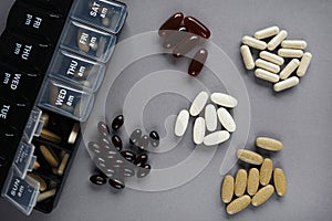 Pillbox by day next to different dietary supplements and tablets