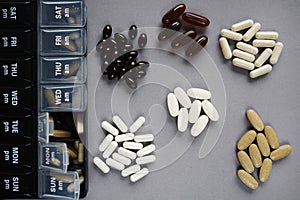 Pillbox by day next to different dietary supplements and tablets
