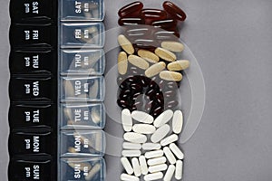Pillbox by day next to different dietary supplements and tablets