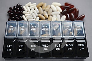 Pillbox by day next to different dietary supplements and tablets