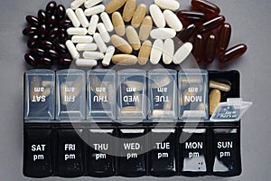 Pillbox by day next to different dietary supplements and tablets