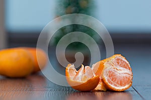 Pilled mandarin on the wooden floor. Christmas tree.