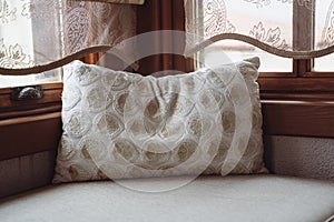 Pillow with embroidery on divan in front of window