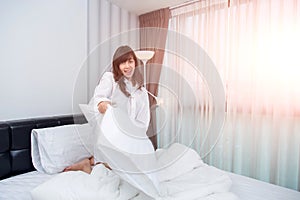 Pillow fight - happy young woman in bed having fun