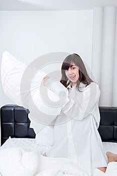 Pillow fight - happy young woman in bed having fun