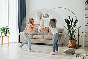 Pillow fight. Kids having fun in the domestic room at daytime together