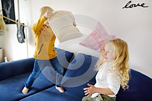 Pillow fight. Mischievous preschooler children jumping on a sofa and hitting each other with pillows. Boy and girl play together