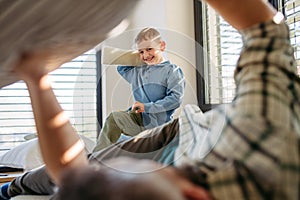 Pillow fight between young son and father. Dad spending time with son at home, having fun.