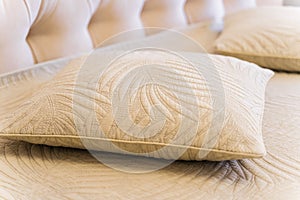 A pillow with a leaf design sits on a bed