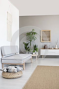 Pillow on pouf next to grey couch in scandi living room interior