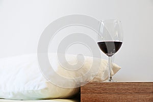 Pillow and wine glass on bedside table. Concept of alcohol drinking abuse and sleeping problem