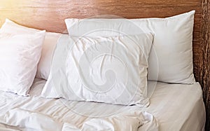 Pillows on the bed with white bedlinen and wooden bedhead