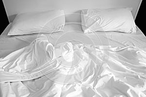 Pillows on messy bed with wrinkle duvet