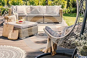 Pillows on rattan couch and table on patio with hanging chair du