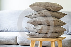 Pillows stacked in a pile on a table.