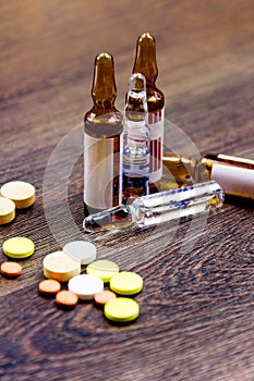 Pills and ampules on wooden background
