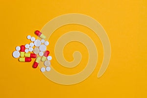 Pills background. Heap of different pills and tablets of different colors on a yellow background. Health care