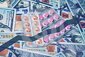 Pills on the background of hundred-dollar bills.