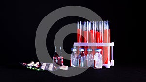 Pills on a background of test tubes with red liquid and ampoules on a black background